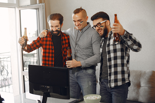 three-guys-celebrating-with-beers-nfl-games-in-front-of-computer